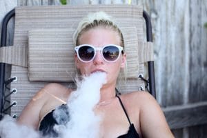 jeune femme qui exhale de la fumée de vape au CBD