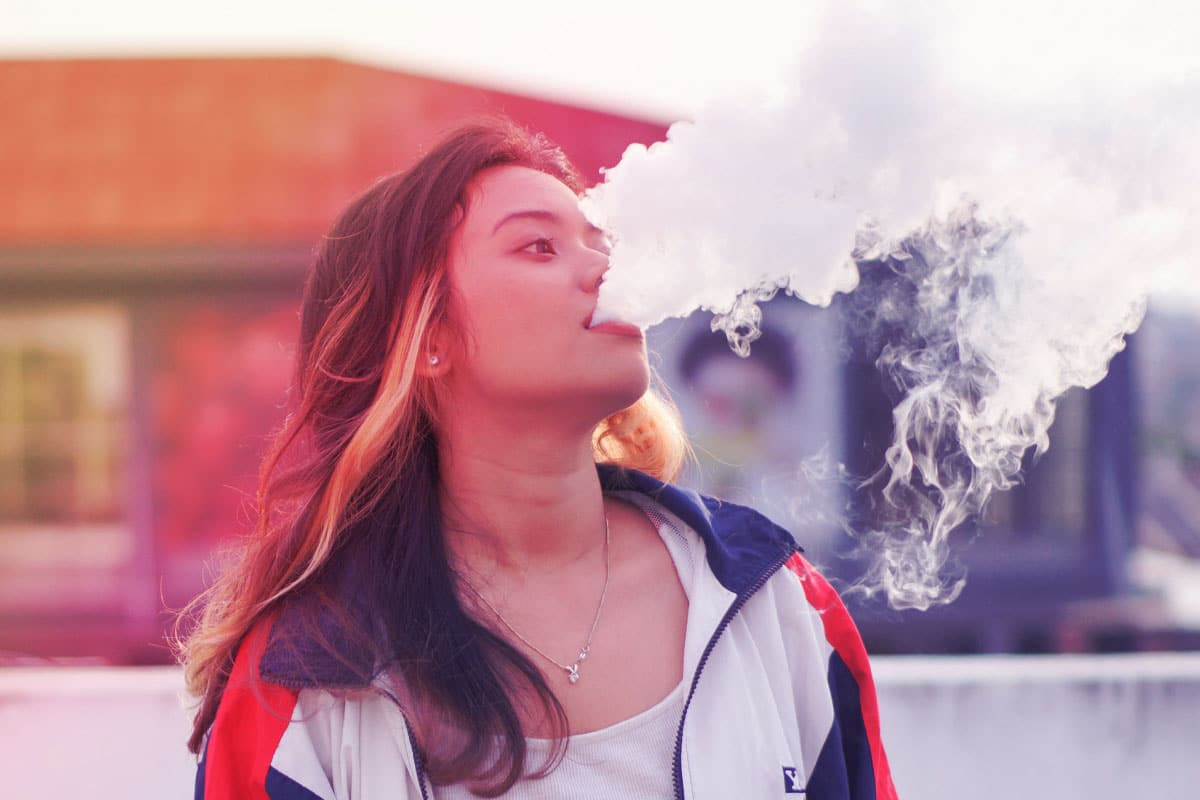 femme qui vapote en exhalant de la vapeur