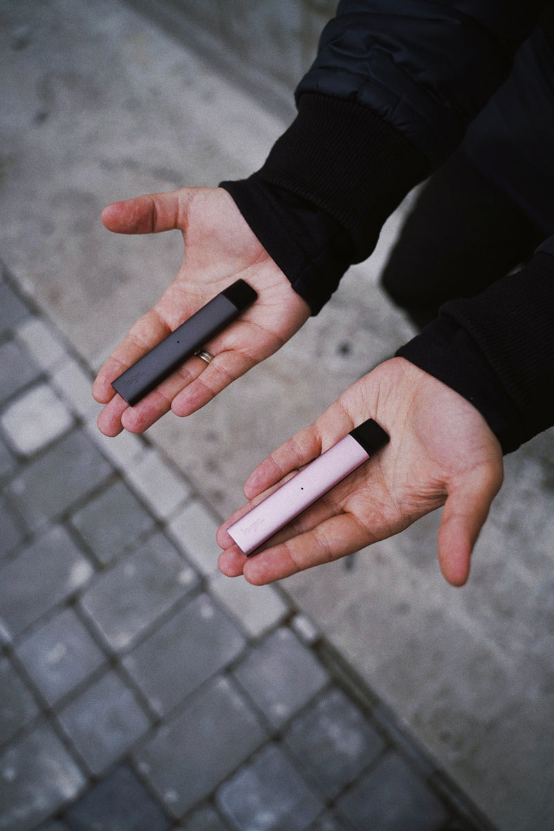 homme qui tient des vape pens dans ses mains