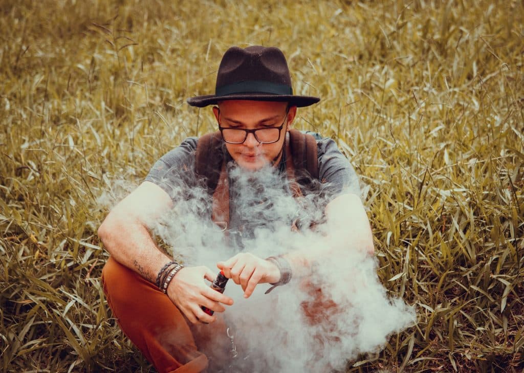 adolescent vapotant une cigarette électronique dans la nature