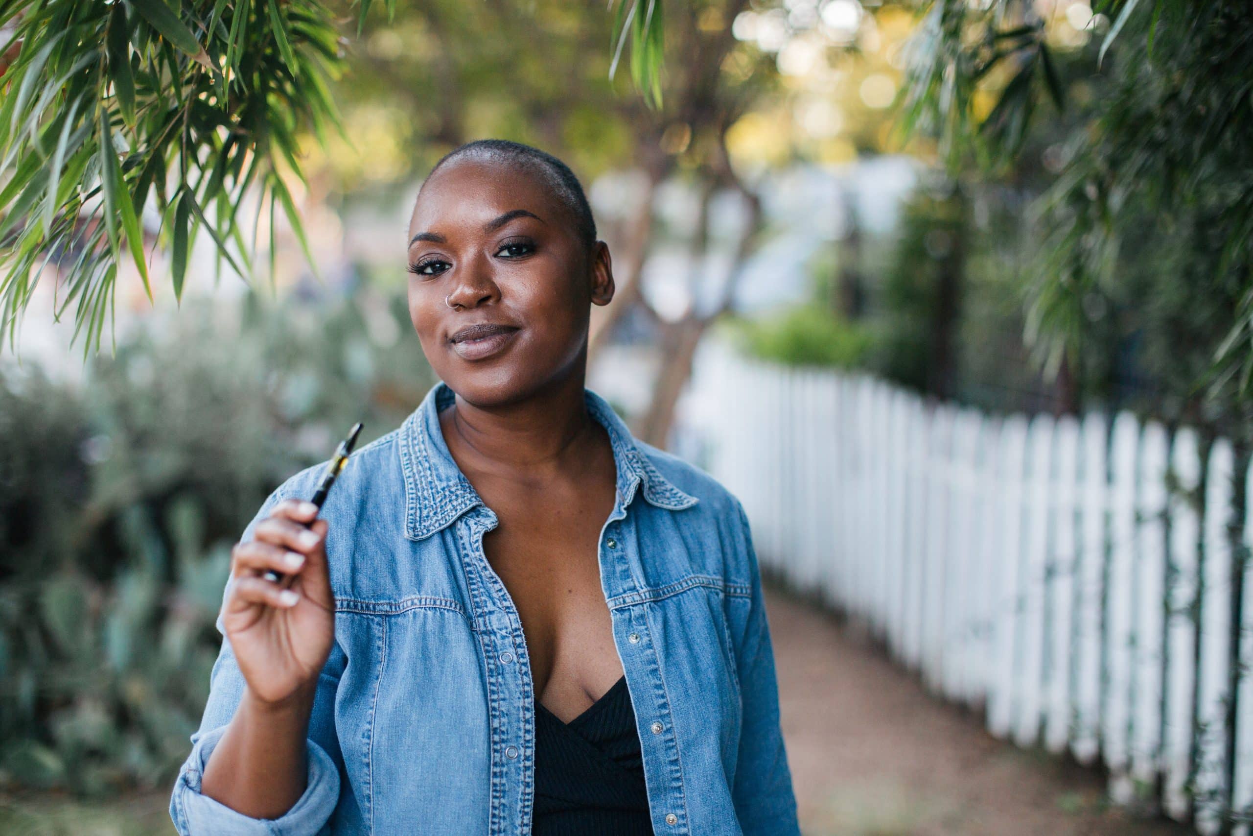 femme noire fumant une cigarette électronique en éxtérieur