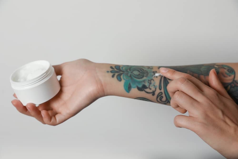 femme qui s'applique de la crème CBD sur son tatouage